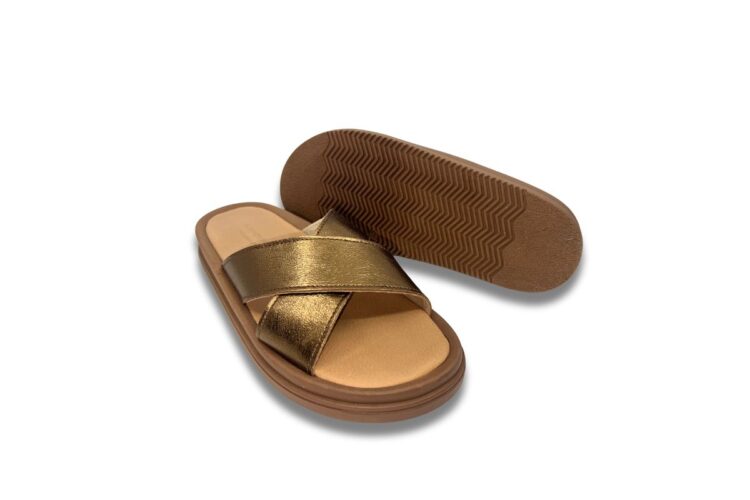 Brown sandals with metallic gold crisscross straps; one sandal is upright, and the other shows the zigzag-patterned sole.