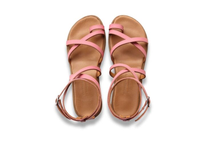 A pair of tan sandals with pink crisscross straps and ankle buckles, photographed from above on a white background.