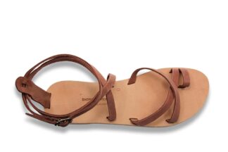 Brown strappy leather sandal with an ankle strap, flat sole, and minimalist design on a white background.
