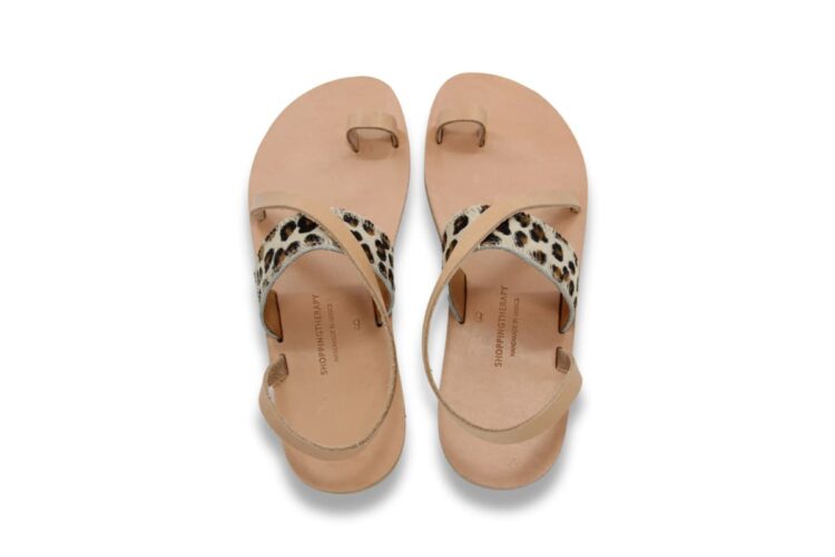 Sandales en cuir naturel vachetta beige avec une bride sur le coup de pied à imprimé léopard, une boucle d'orteil et une bride diagonal sur le coup de pied et qui passe derrière la cheville, affichée sur un fond blanc. Vue supérieure de la paire. Modèle Patmos Leo.