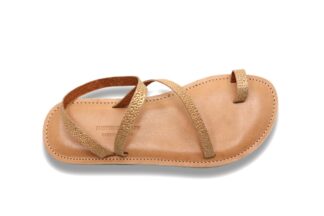 Une sandale en cuir doré avec une semelle plate, deux lanières texturées qui se croisent sur le pied et une sur le grand orteil.